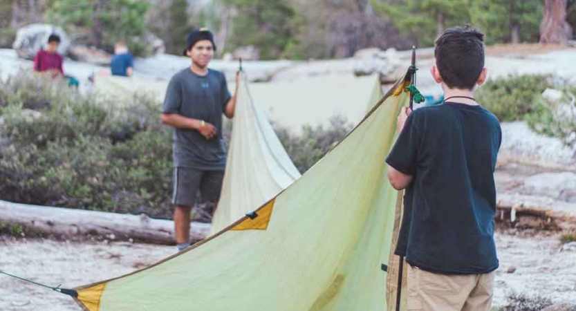 two students work together to set up a shelter on an outward bound course